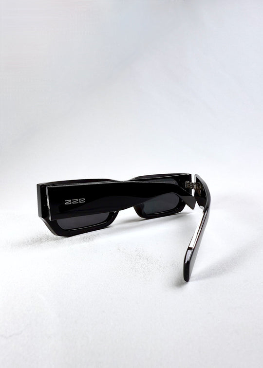 Folded view of Oblivion Trace in Obsidian Black, showcasing the sharp rectangular silhouette and Aze logo on the temple. 