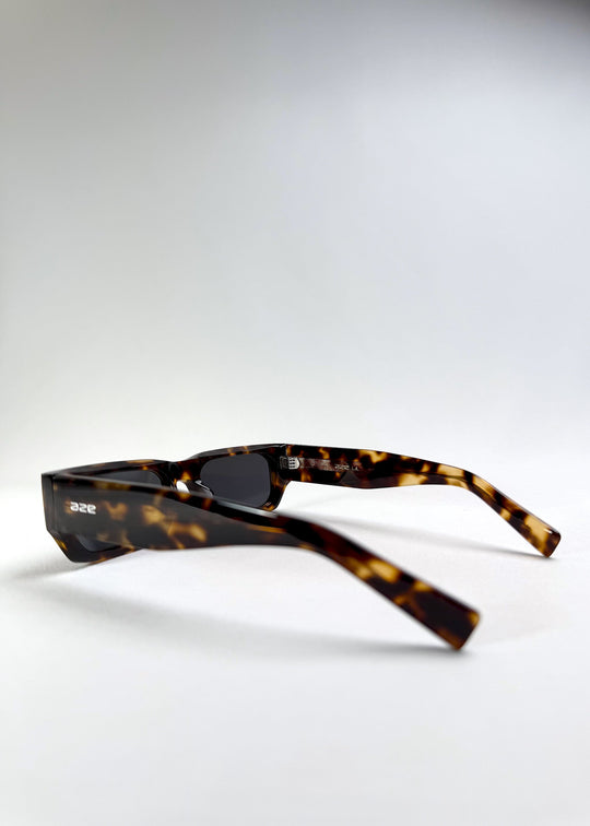 Side view of Oblivion Trace sunglasses in Tortoise, showcasing the thick acetate temple and logo detail. 