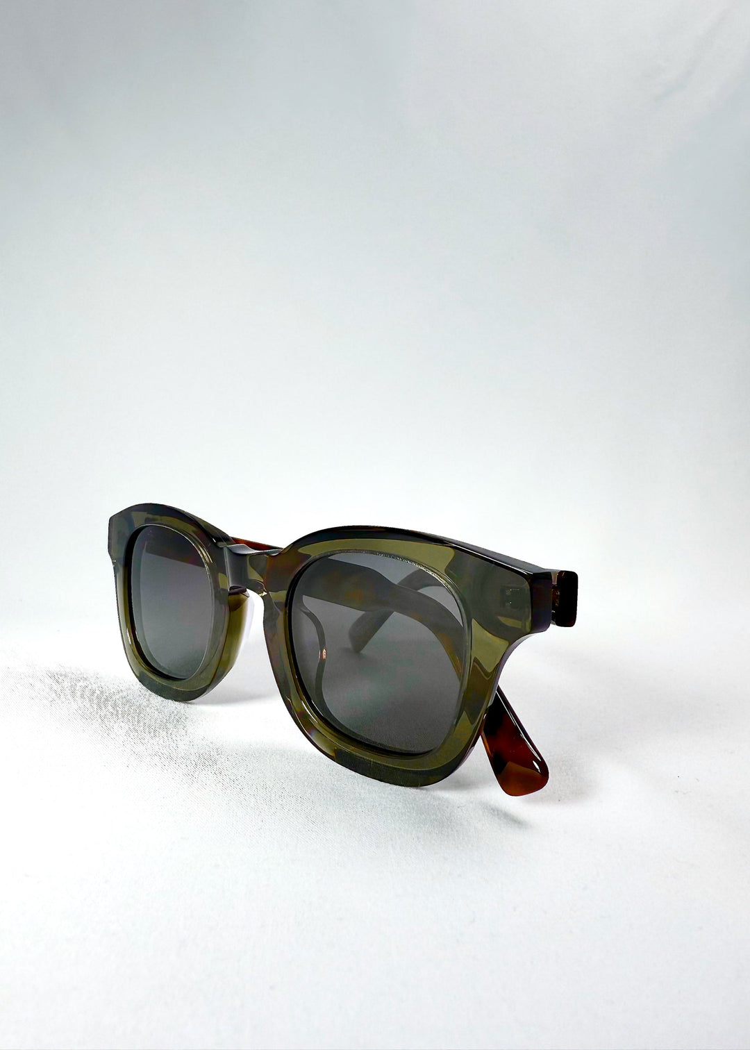 Folded three-quarter view of Phantom Verge in Ash Tortoise, showing the olive-green acetate front and tortoiseshell temple arms. 