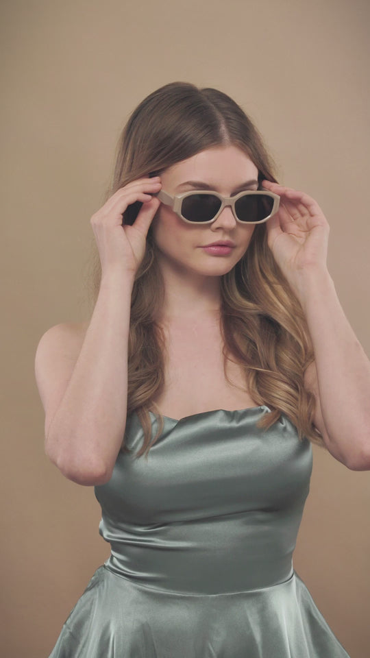 Lifestyle video of a female model wearing Lyra sunglasses in Creamy Beige. 