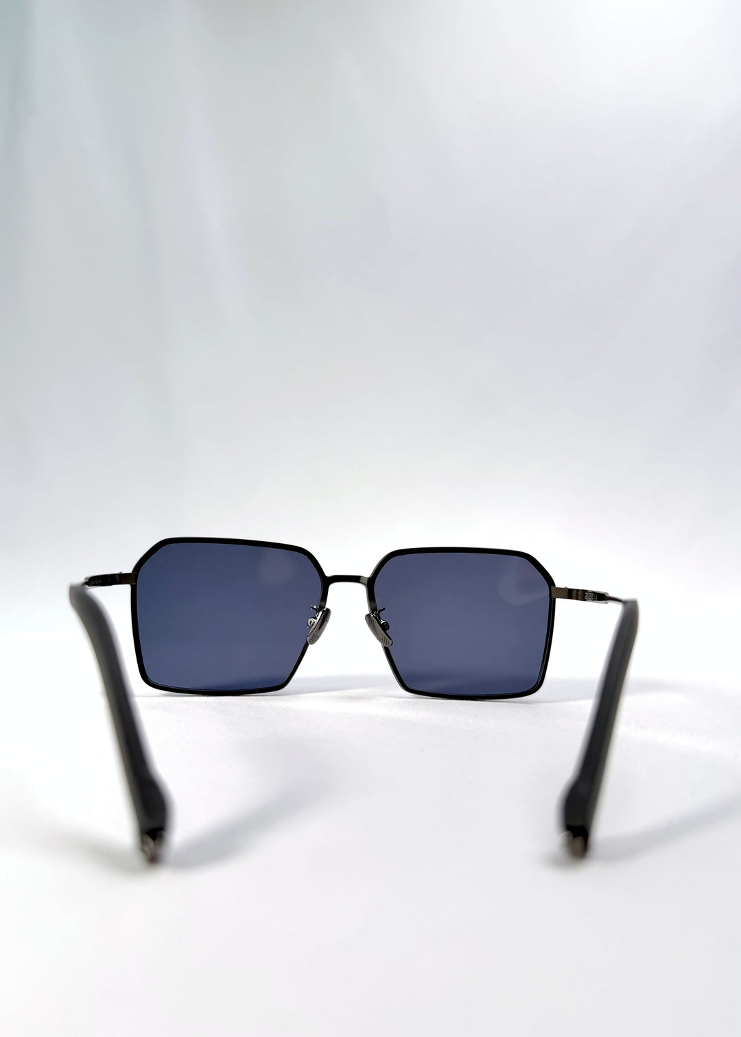 Back view of Rigel sunglasses in Blue Graphite, featuring an ultra-light frame with titanium temples, geometric lens shape, and polarized lenses, showing the inside frame and open temples. 