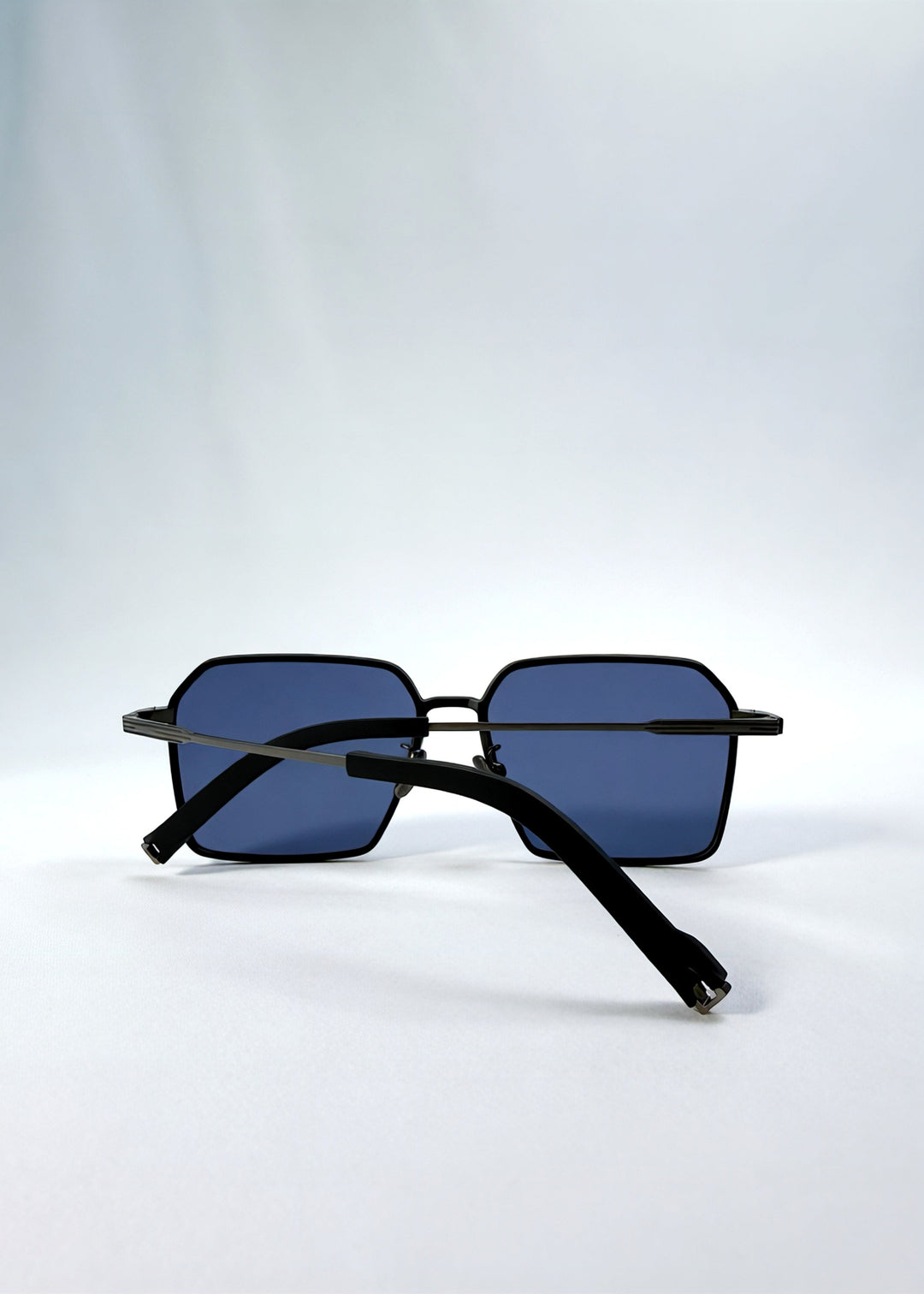 Folded view of Rigel sunglasses in Blue Graphite, featuring an ultra-light frame with titanium temples, geometric lens shape, and polarized lenses, showing the folded temples and frame profile. 