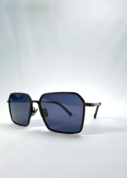 Three-quarter front view of Rigel sunglasses in Matte Black, featuring ultra-light titanium frame, geometric lens shape, and polarized lenses, showing the front shape and temple profile.