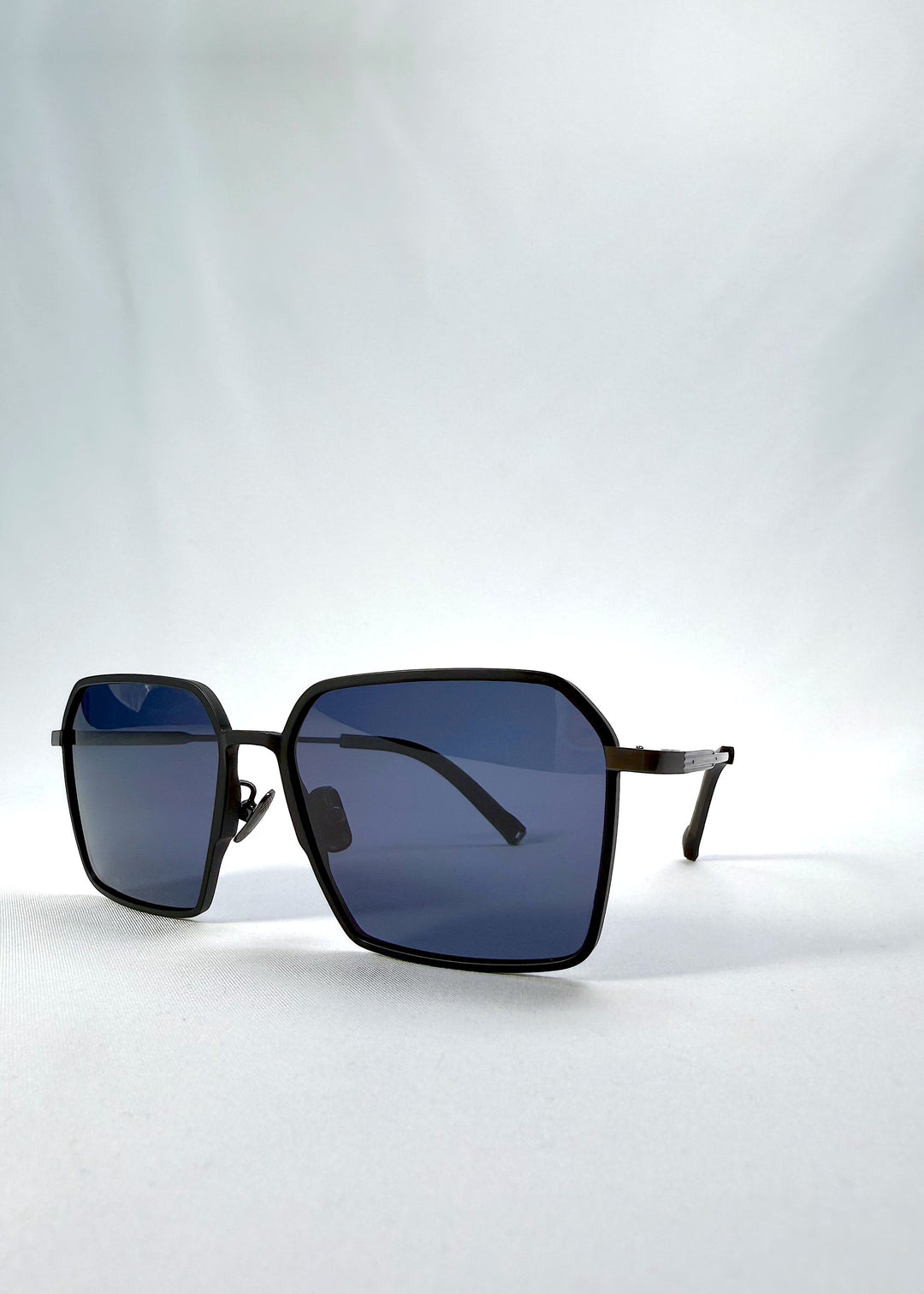 Three-quarter front view of Rigel sunglasses in Blue Graphite, featuring an ultra-light frame with titanium temples, geometric lens shape, and polarized lenses, showing the front shape and temple profile. 