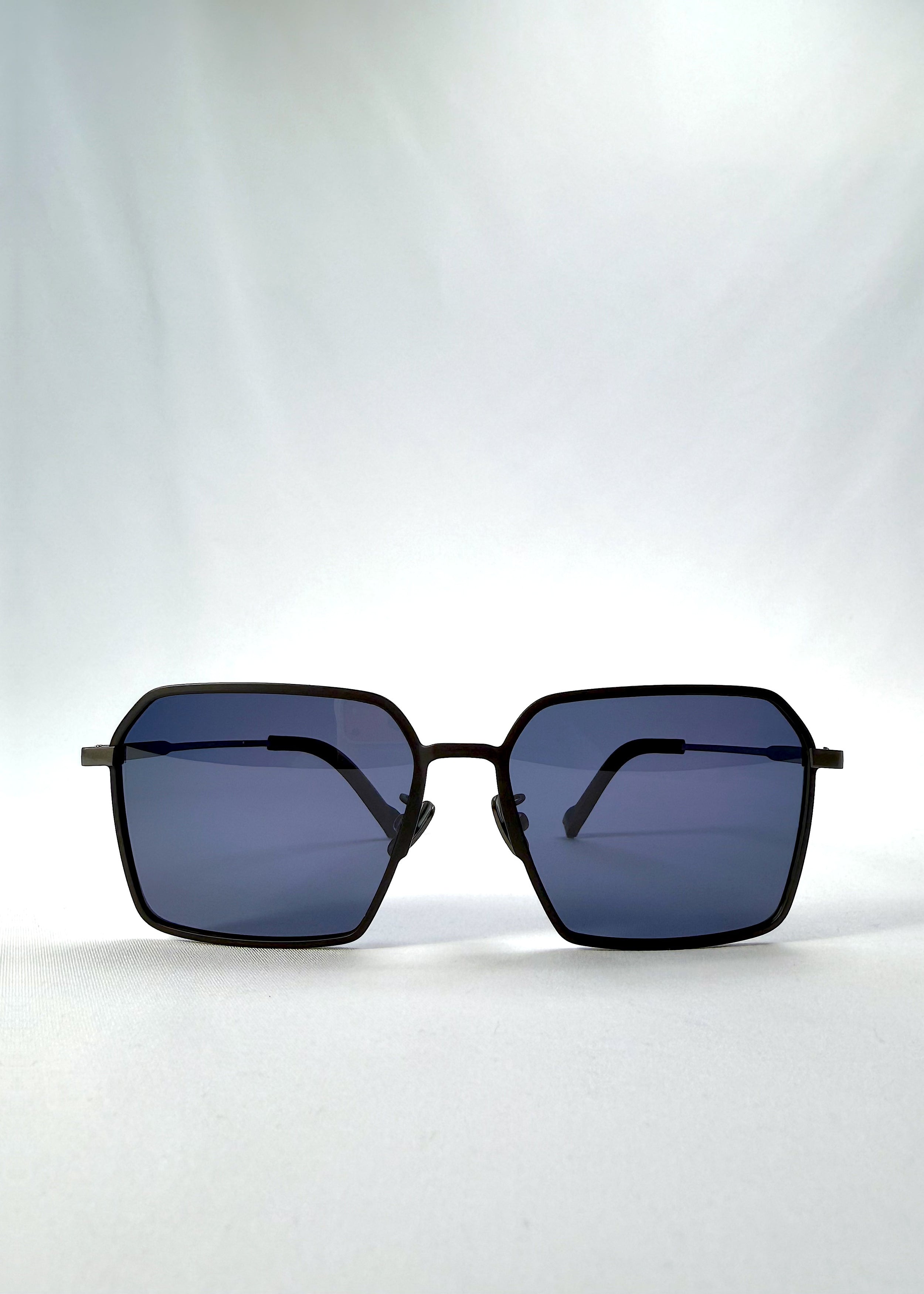 Front view of Rigel sunglasses in Matte Black, featuring ultra-light titanium frame, geometric lens shape, and polarized lenses, showing the full front silhouette.