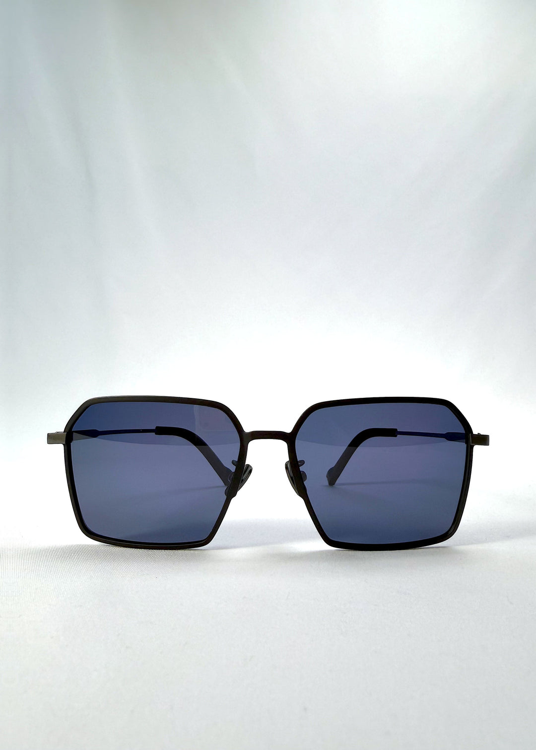 Front view of Rigel sunglasses in Blue Graphite, featuring an ultra-light frame with titanium temples, geometric lens shape, and polarized lenses, showing the full front silhouette. 
