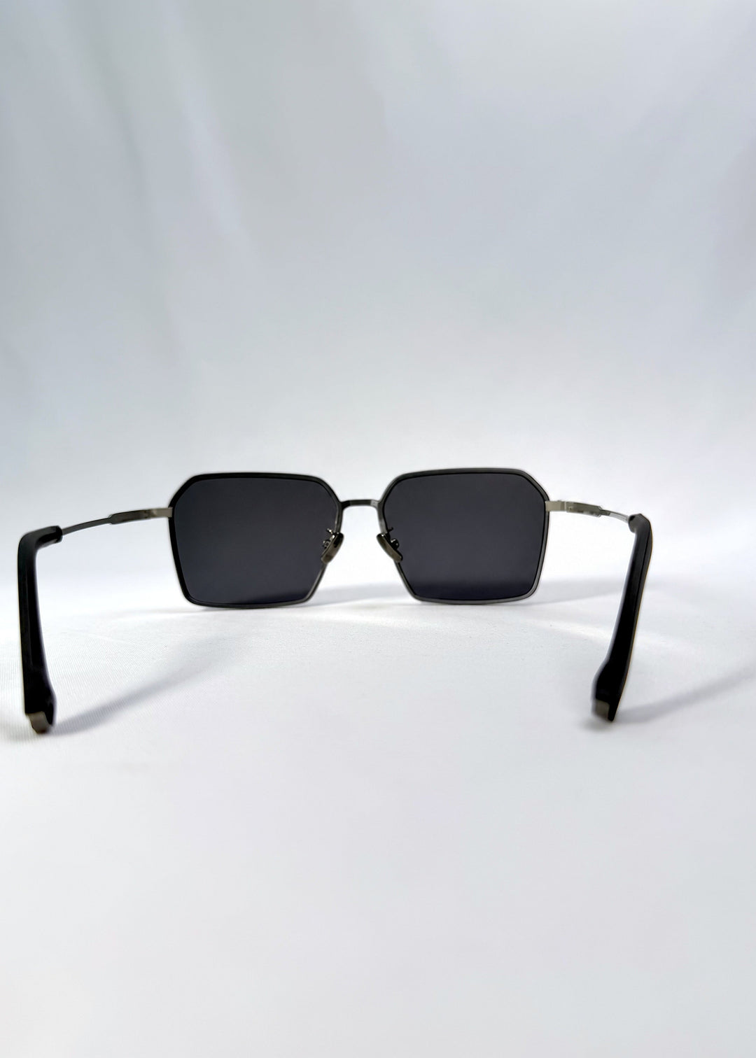 Back view of Rigel sunglasses in Gunmetal Ash, featuring an ultra-light frame with titanium temples, geometric lens shape, and polarized lenses, showing the inside frame and open temples. 