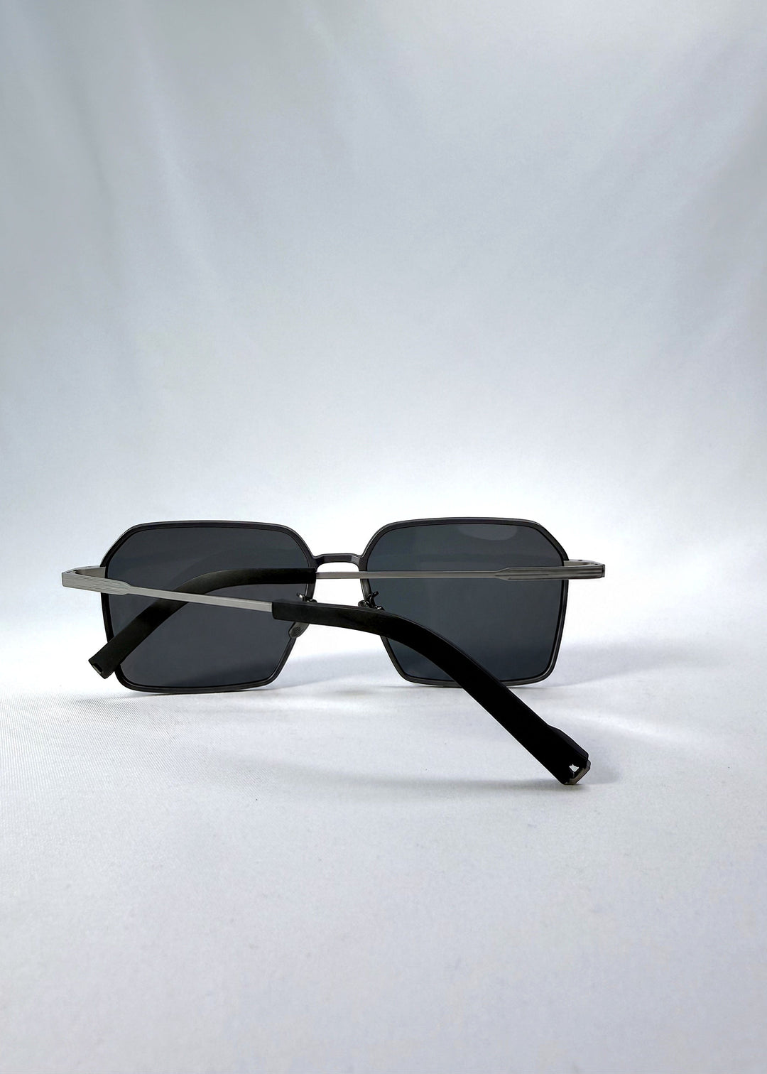Folded view of Rigel sunglasses in Gunmetal Ash, featuring an ultra-light frame with titanium temples, geometric lens shape, and polarized lenses, showing the folded temples and frame profile. 
