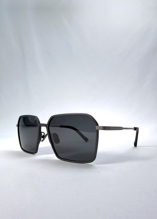 Three-quarter front view of Rigel sunglasses in Gunmetal Ash, featuring an ultra-light frame with titanium temples, geometric lens shape, and polarized lenses, showing the front shape and temple profile. 