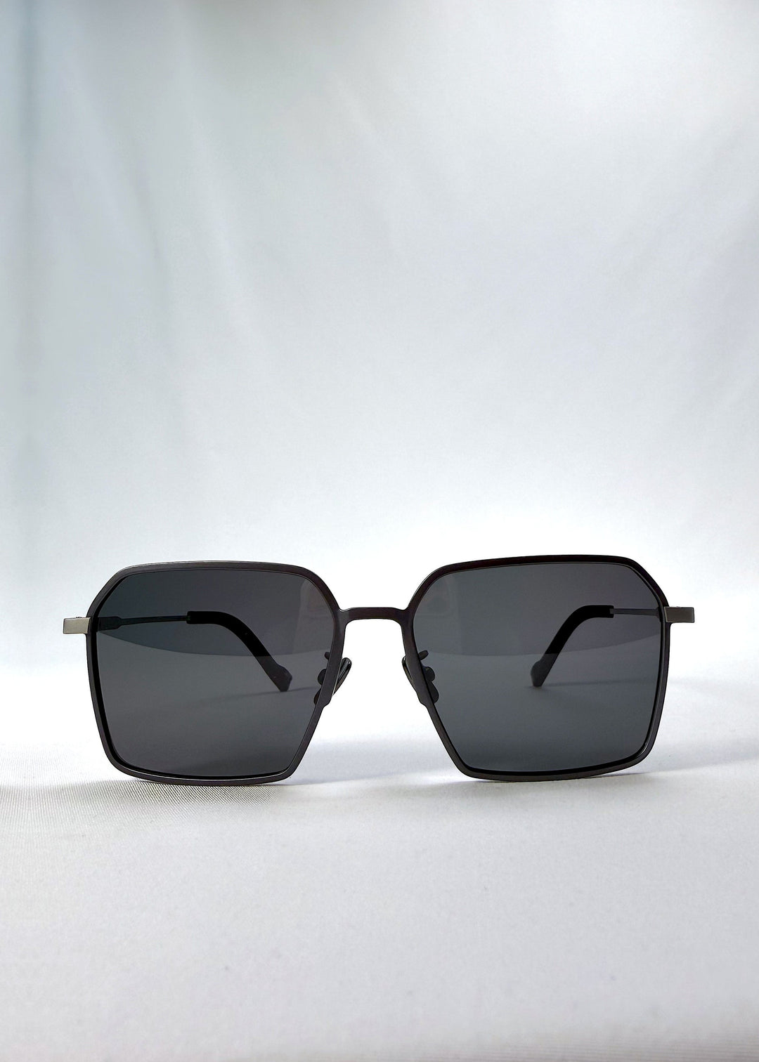 Front view of Rigel sunglasses in Gunmetal Ash, featuring an ultra-light frame with titanium temples, geometric lens shape, and polarized lenses, showing the full front silhouette. 