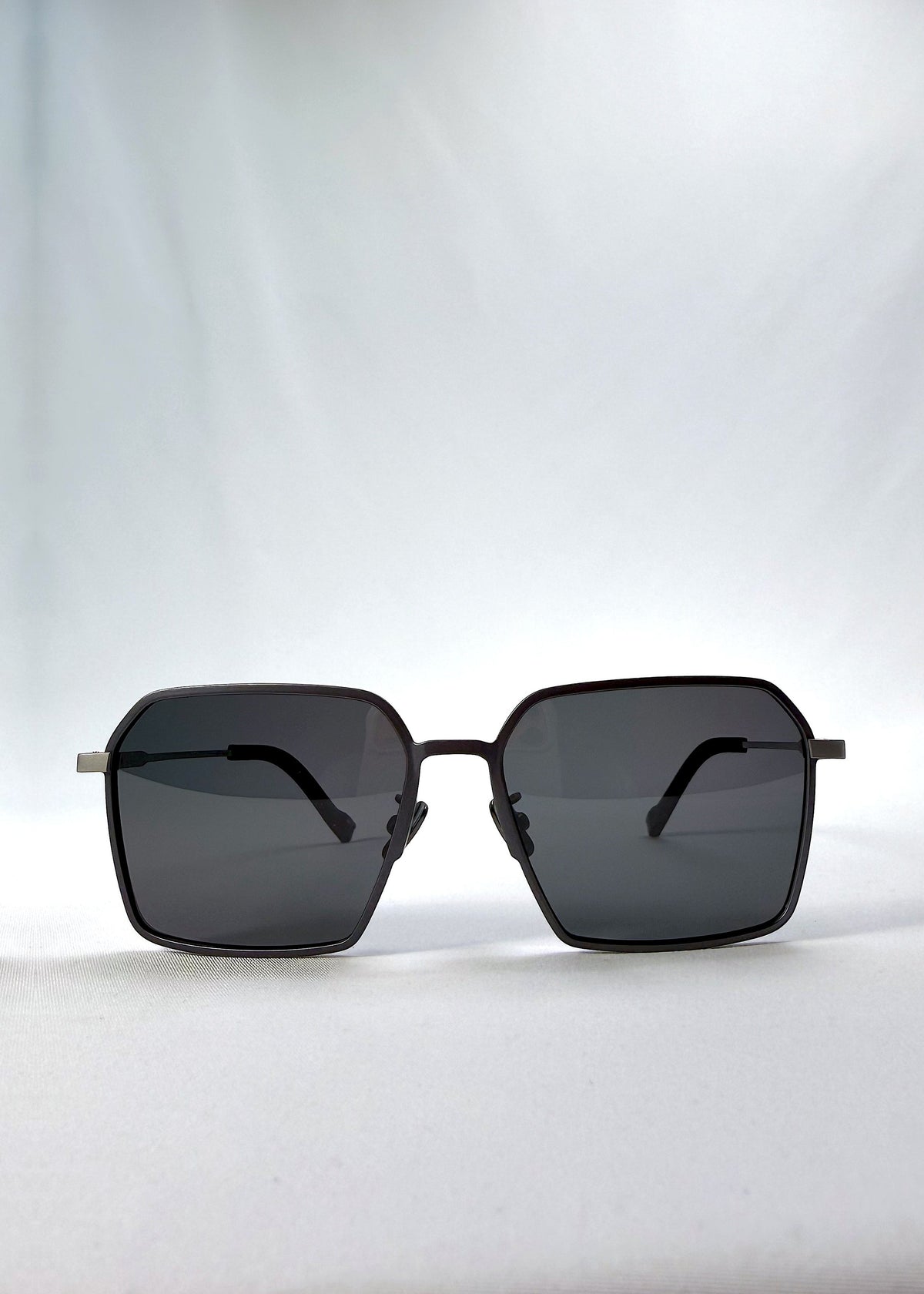 Front view of Rigel sunglasses in Gunmetal Ash, featuring an ultra-light frame with titanium temples, geometric lens shape, and polarized lenses, showing the full front silhouette.
