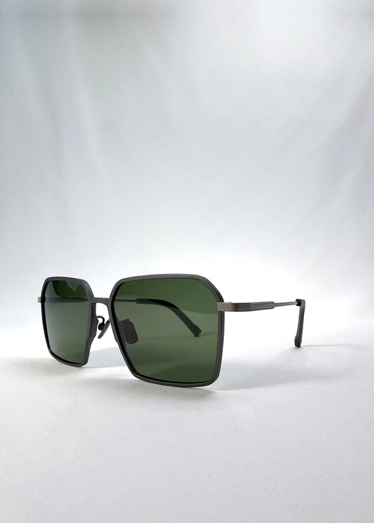 Three-quarter front view of Rigel sunglasses in Olive Smoke, featuring an ultra-light frame with titanium temples, geometric lens shape, and polarized lenses, showing the front shape and temple profile. 