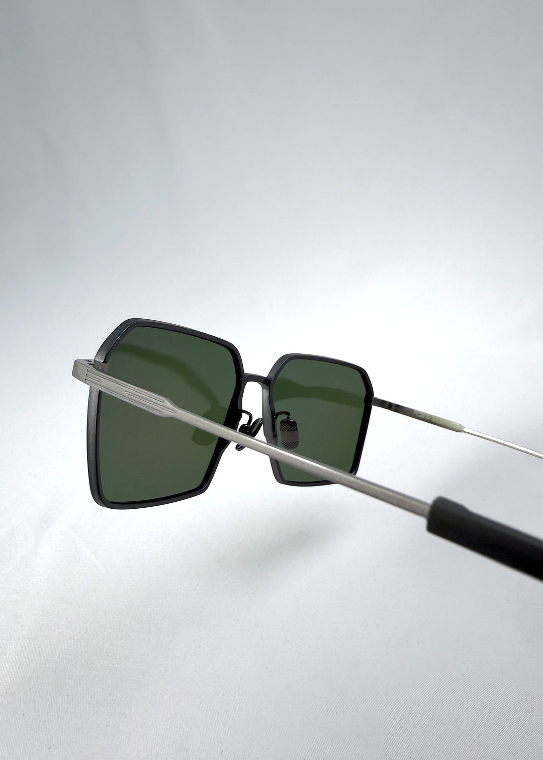 Close-up temple detail view of Rigel sunglasses in Olive Smoke, featuring an ultra-light frame with titanium temples, geometric lens shape, and polarized lenses, showing the temple arm and hinge area. 