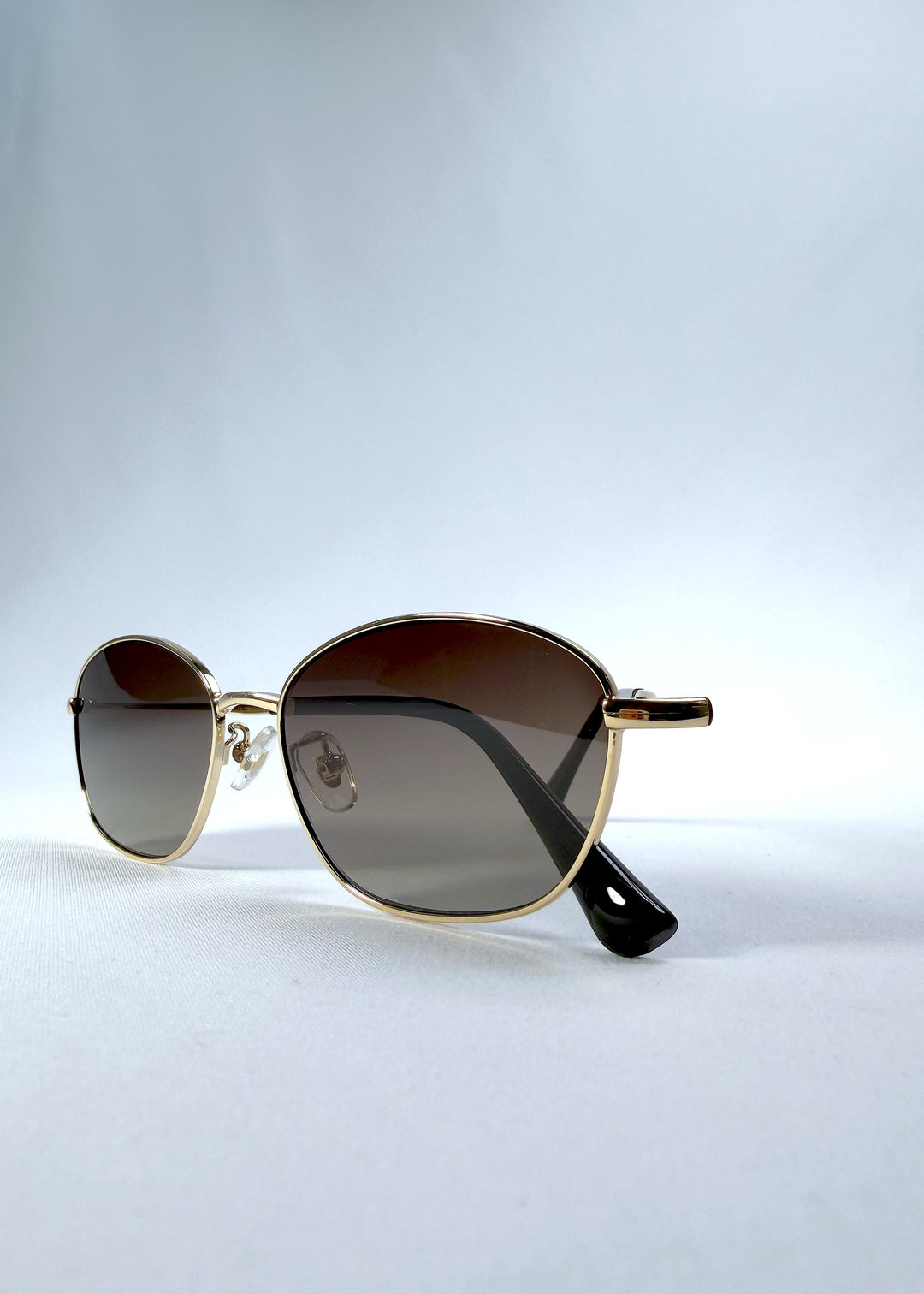 Folded front view of Selene Line sunglasses in Amber Gold, featuring a slim gold-tone oval metal frame and amber gradient lenses, showing the front frame and folded temples.