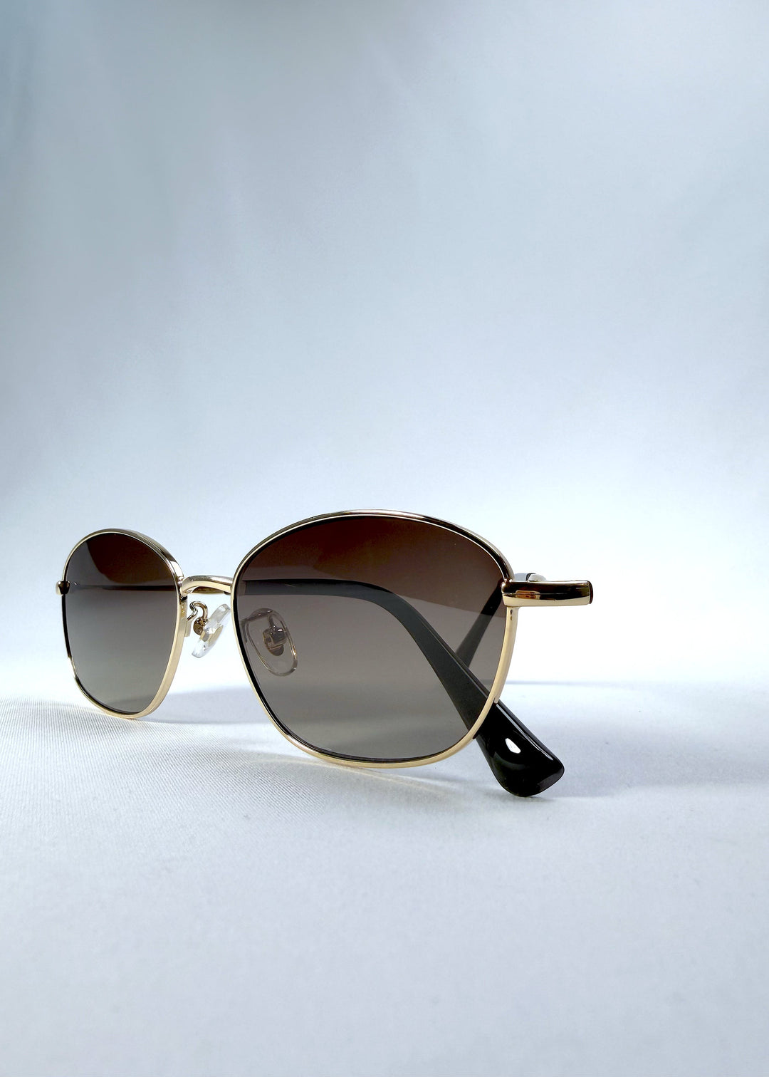 Folded front view of Selene Line sunglasses in Amber Gold, featuring a slim gold-tone oval metal frame and amber gradient lenses, showing the front frame and folded temples. 