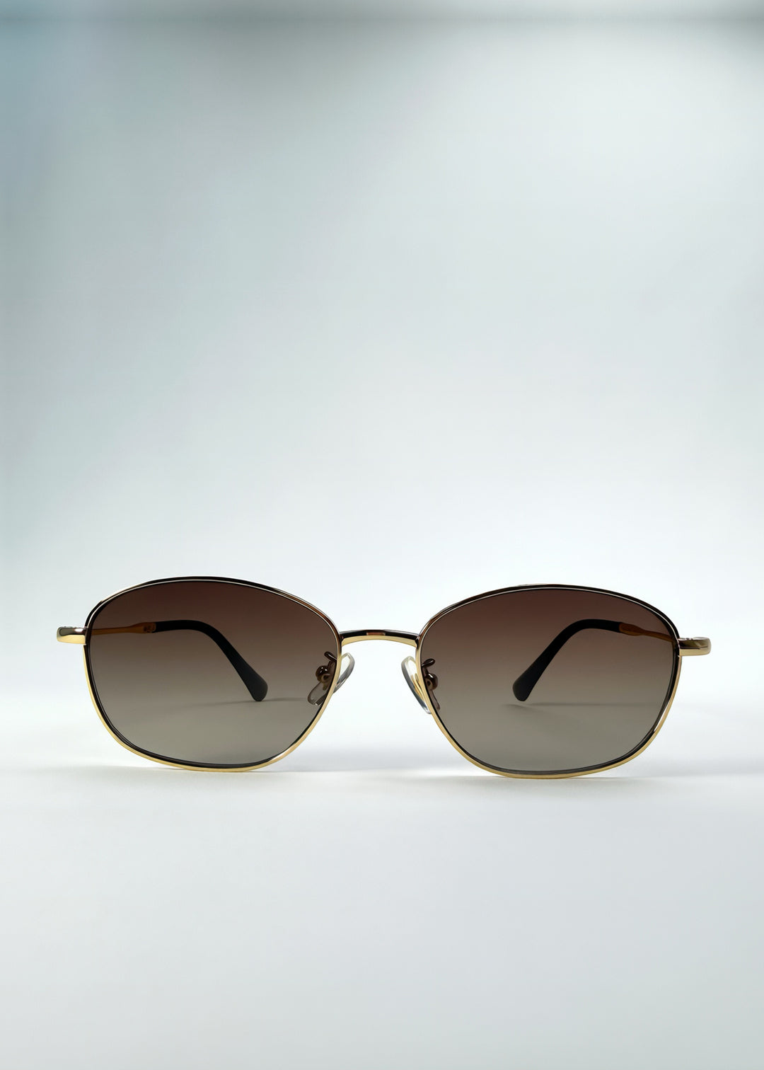 Front view of Selene Line sunglasses in Amber Gold, featuring a slim gold-tone oval metal frame and amber gradient lenses, showing the full front silhouette.