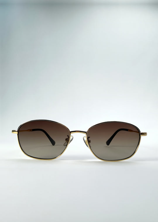 Front view of Selene Line sunglasses in Amber Gold, featuring a slim gold-tone oval metal frame and amber gradient lenses, showing the full front silhouette.