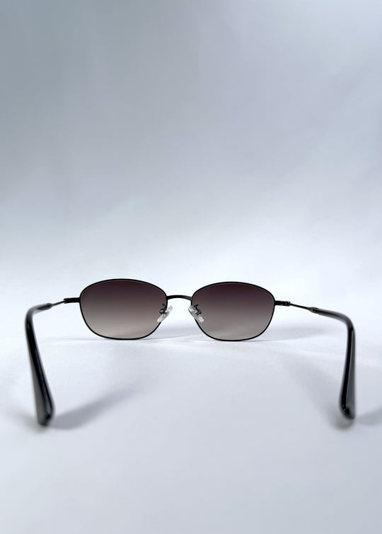 Back view of Selene Line sunglasses in Matte Black, featuring a slim matte black oval metal frame and smoky gradient lenses, showing the inside frame and open temples.