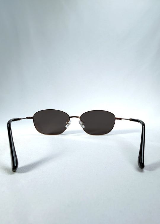 Back view of AZE Selene Line sunglasses in Mocha Alloy, featuring a slim bronze-tone oval metal frame and smoky brown lenses, showing the inner frame and open temples.