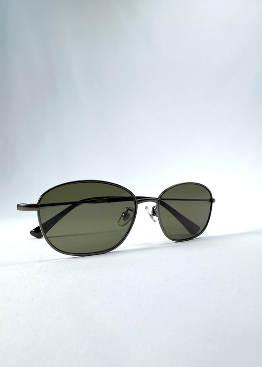 Folded view of AZE Selene Line sunglasses in Sage Gunmetal, featuring a slim gunmetal oval metal frame and sage-green lenses, showing the folded temples and frame profile.