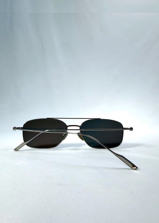 Folded back view of Seren Arc sunglasses in Gunmetal Veil, featuring gunmetal frame and dark tinted lenses, showing the folded temples and back structure. 