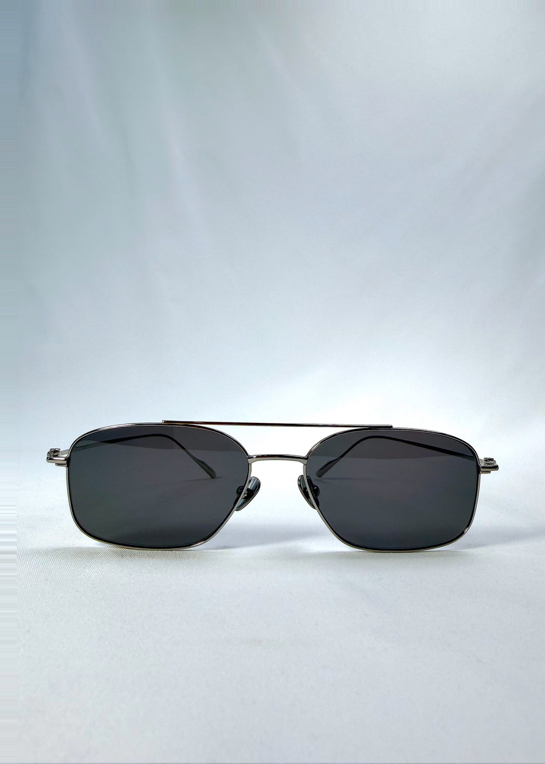 Front view of Seren Arc sunglasses in Gunmetal Veil, featuring gunmetal frame and dark tinted lenses, showing the full front silhouette. 