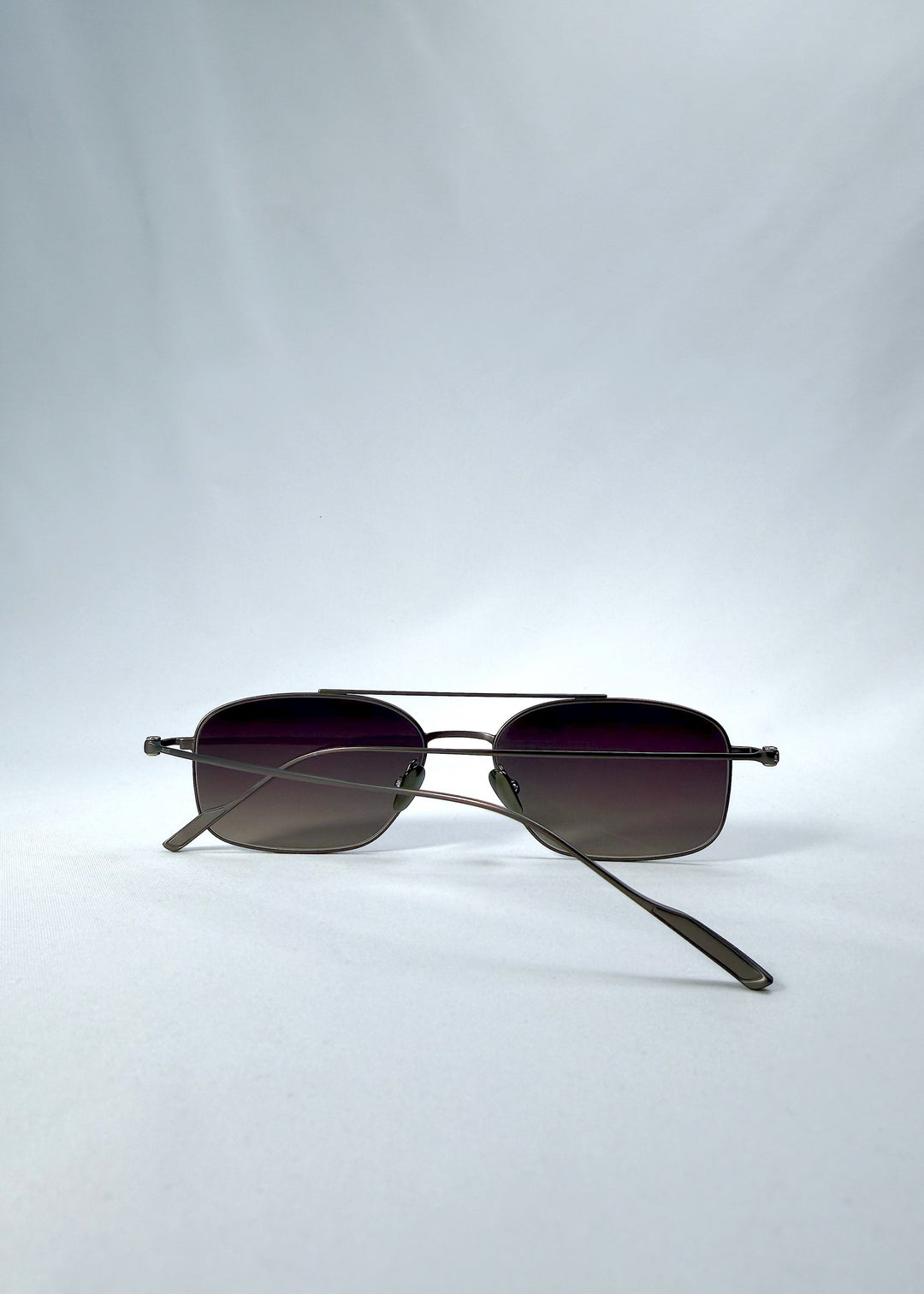 Folded back view of Seren Arc sunglasses in Mocha Alloy, featuring mocha metal frame and rose-brown lenses, showing the folded temples and back structure. 