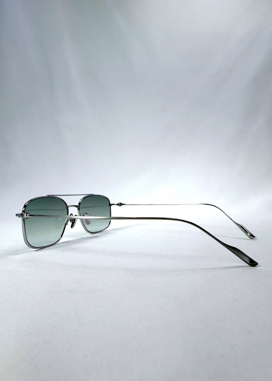 Side-angle view of Seren Arc sunglasses in Moonlit Silver, featuring silver metal frame and pale green lenses, showing the lens shape and side temple profile.