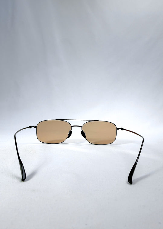 Back view of Seren Arc sunglasses in Obsidian Black, featuring black metal frame and warm brown lenses, showing the inside frame and open temples. 