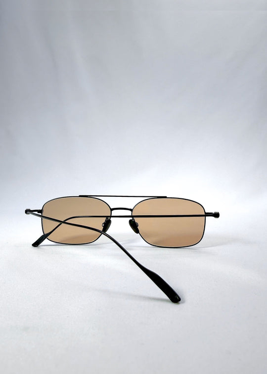 Folded back view of Seren Arc sunglasses in Obsidian Black, featuring black metal frame and warm brown lenses, showing the folded temples and back structure. 