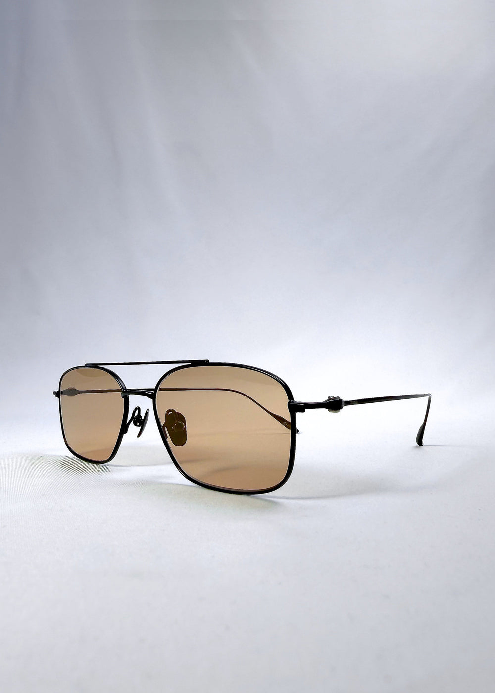 Three-quarter front view of Seren Arc sunglasses in Obsidian Black, featuring black metal frame and warm brown lenses, showing the front shape and temple profile. #color_obsidian-black