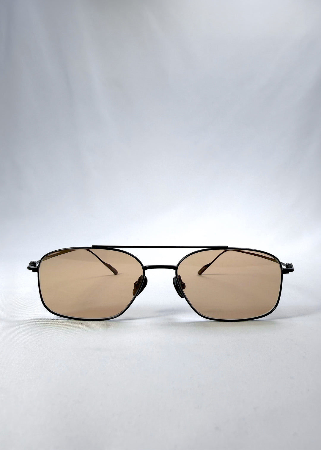 Front view of Seren Arc sunglasses in Obsidian Black, featuring black metal frame and warm brown lenses, showing the full front silhouette.