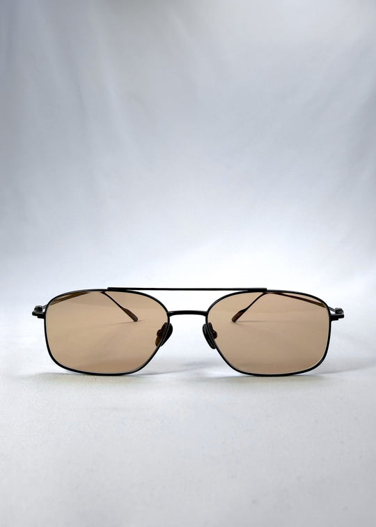 Front view of Seren Arc sunglasses in Obsidian Black, featuring black metal frame and warm brown lenses, showing the full front silhouette. 