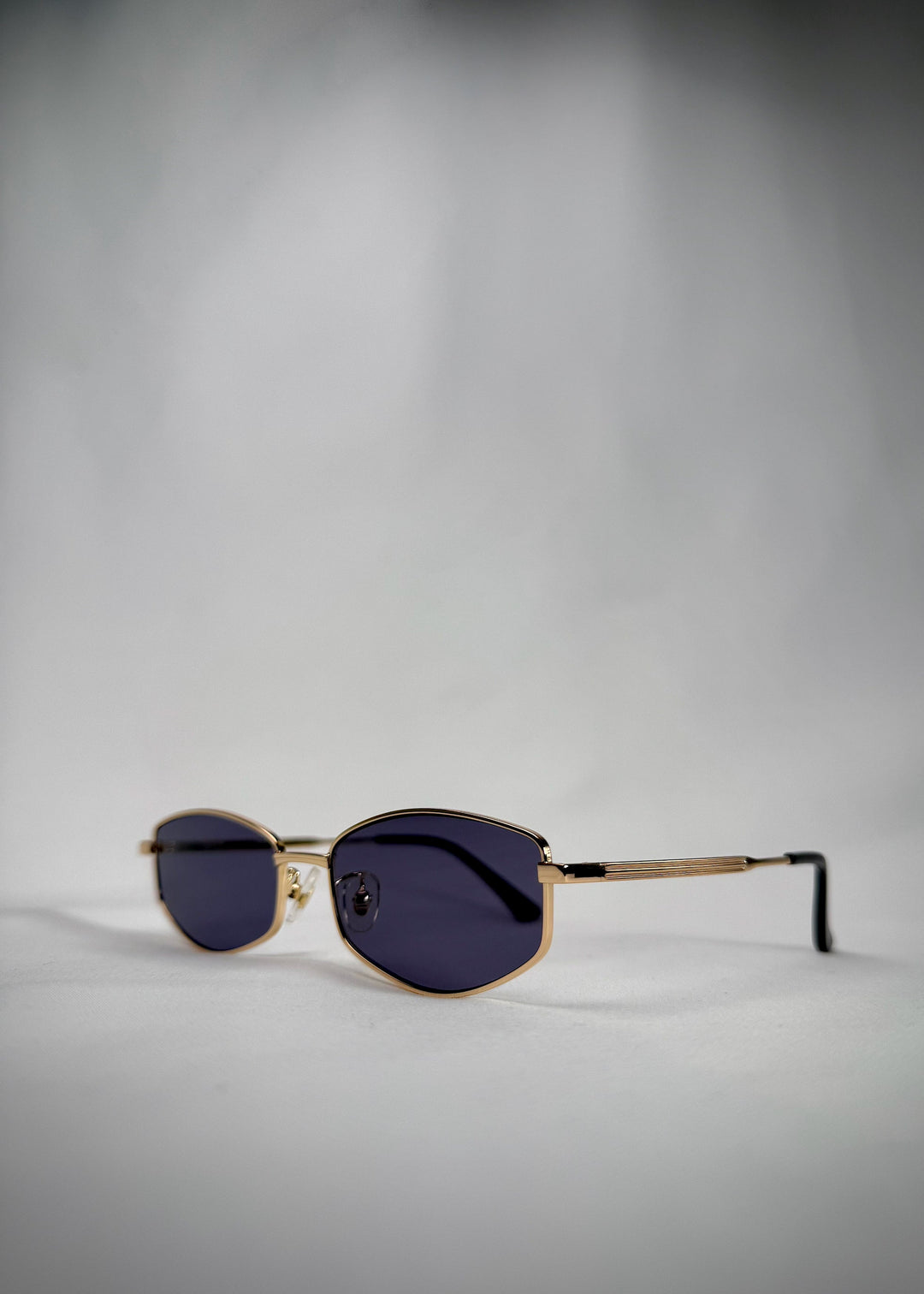 Angled view of Sirius B - Gold stainless steel sunglasses, featuring a lightweight frame and sophisticated blue-gray lenses. 