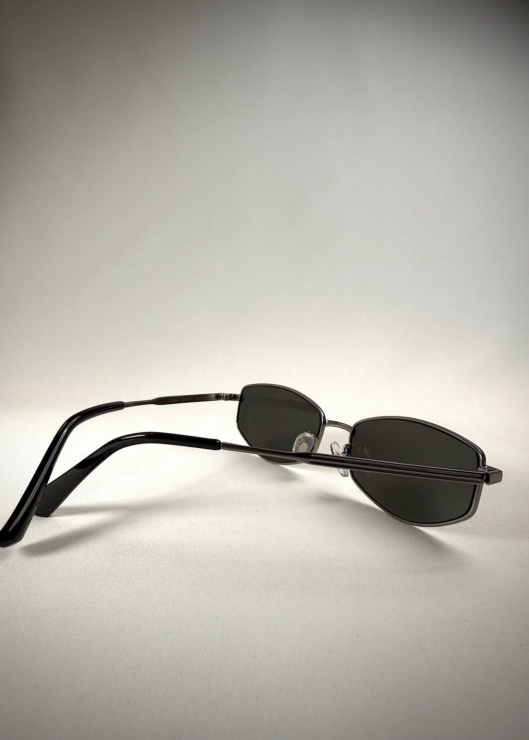 Back-angle view of Sirius B - Matte Black stainless steel sunglasses, highlighting the sleek metal frame, neutral gray lenses, and curved temple arms for a secure fit. 