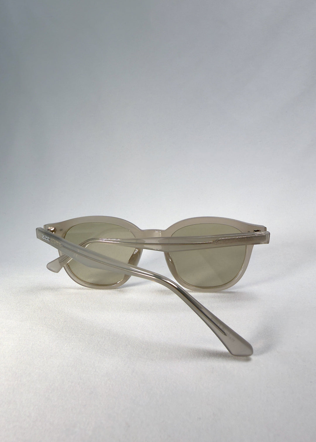 Elvor sunglasses in Glacier Smoke, back-angle view showing frosted grey-white acetate frame and tea-tinted lenses. 