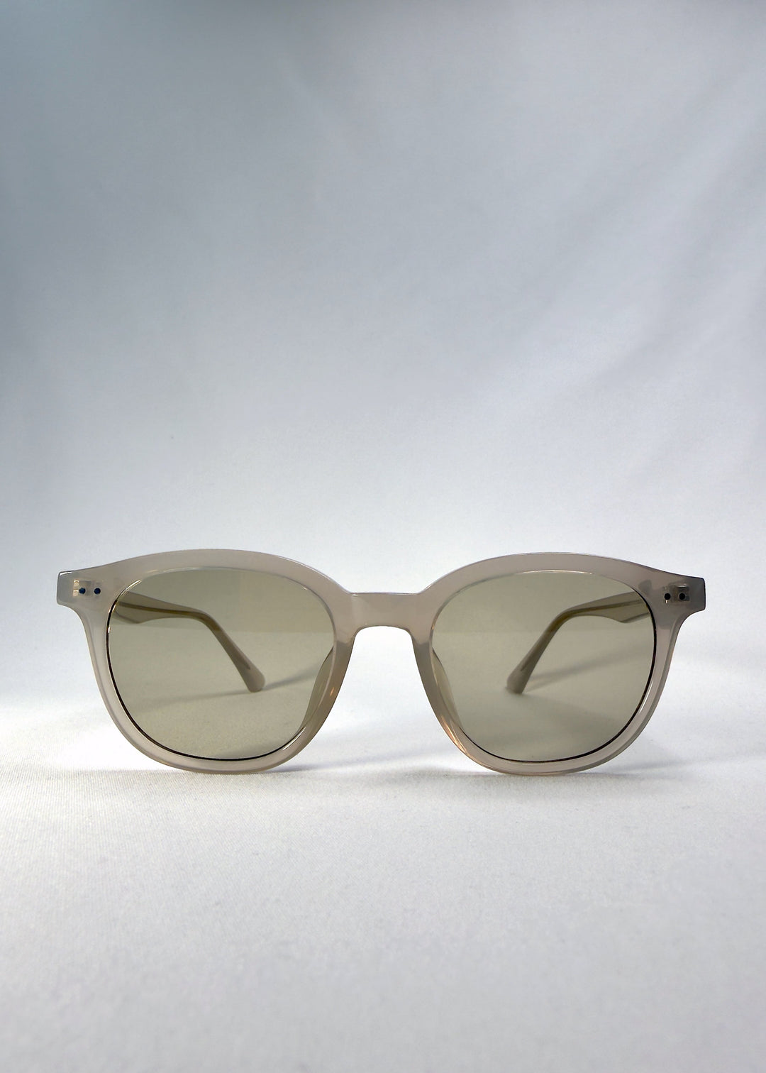 Front view of Elvor sunglasses in Glacier Smoke, showing the frosted grey-white acetate frame and tea-tinted round lenses. 
