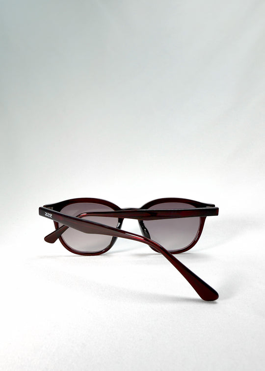Folded-angle view of Elvor Softint sunglasses in Mulberry Mist showing the slender temples and polished acetate arms in translucent wine red.