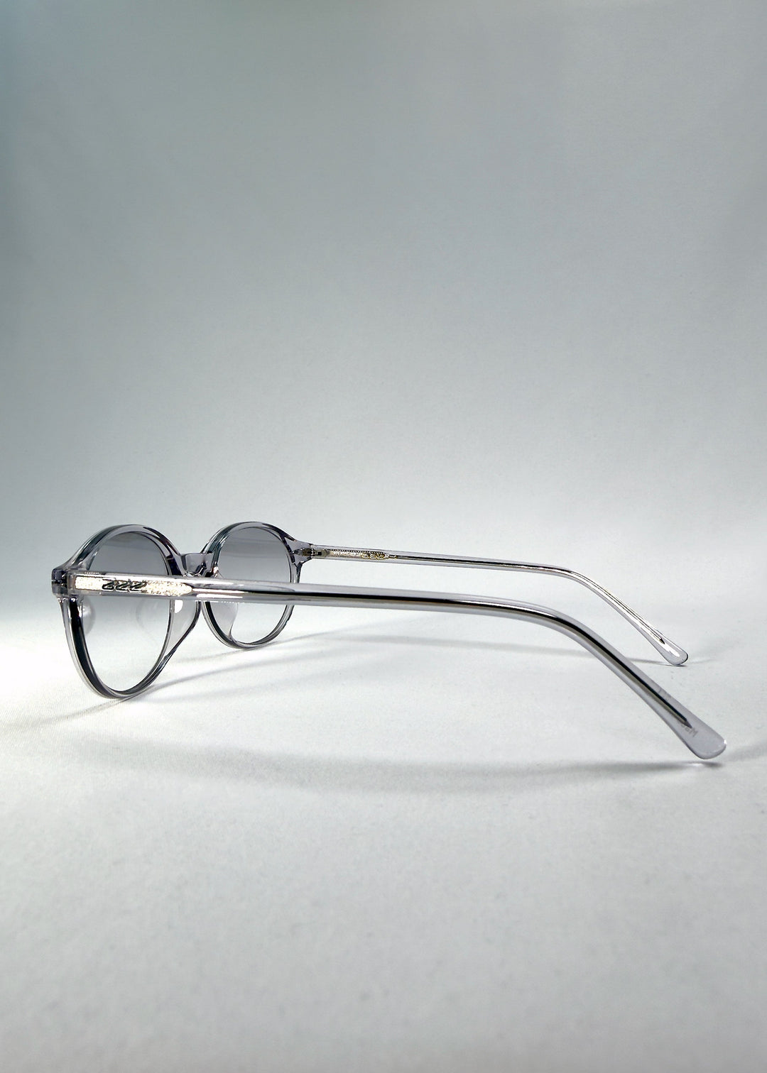 Back-angle view of Glint Softint sunglasses in Crystal Verge showing translucent grey acetate frame and gradient smoke lenses. 