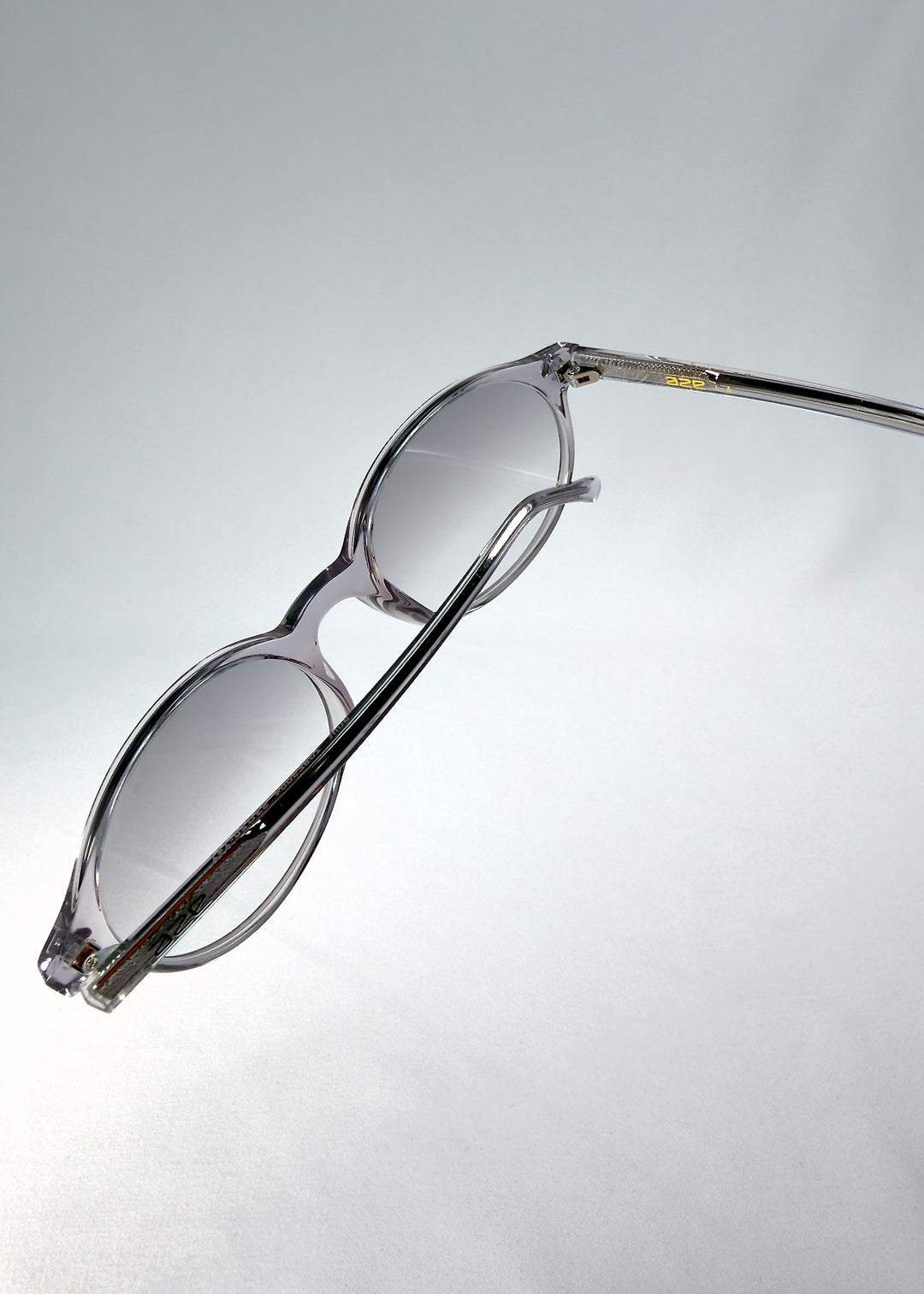 Top-angle close-up of Glint Softint sunglasses in Crystal Verge showing the smooth acetate frame and lens curvature detail.