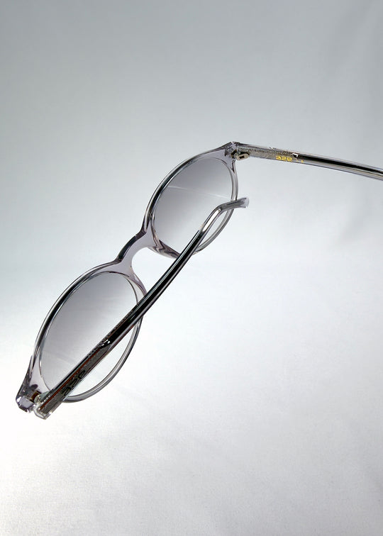 Top-angle close-up of Glint Softint sunglasses in Crystal Verge showing the smooth acetate frame and lens curvature detail.