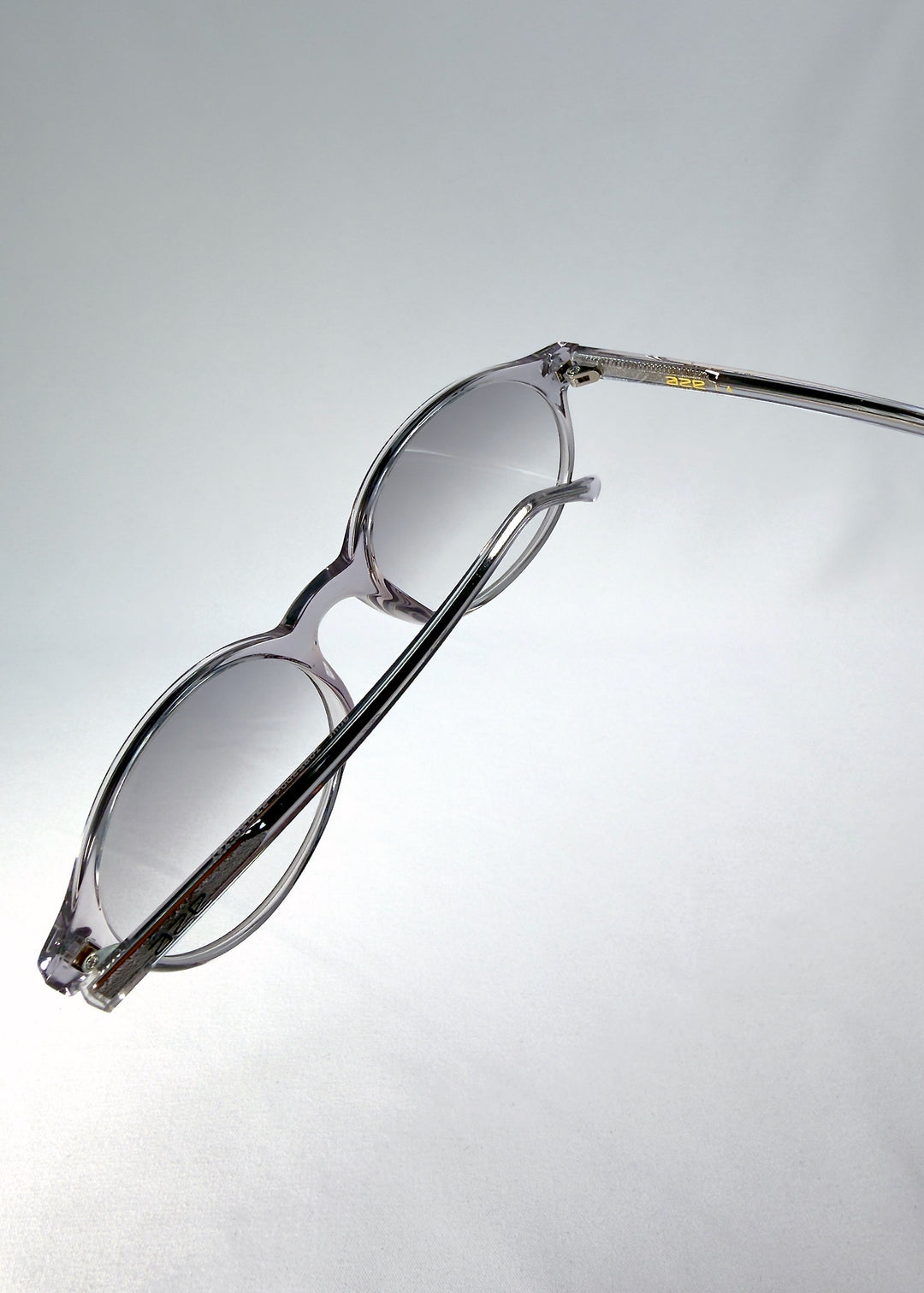 Top-angle close-up of Glint Softint sunglasses in Crystal Verge showing the smooth acetate frame and lens curvature detail. 