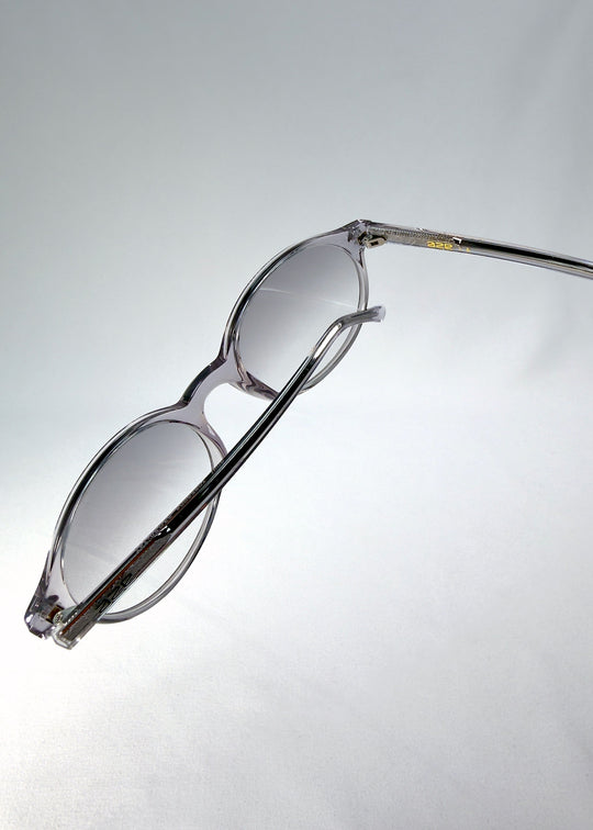 Top-angle close-up of Glint Softint sunglasses in Crystal Verge showing the smooth acetate frame and lens curvature detail. 