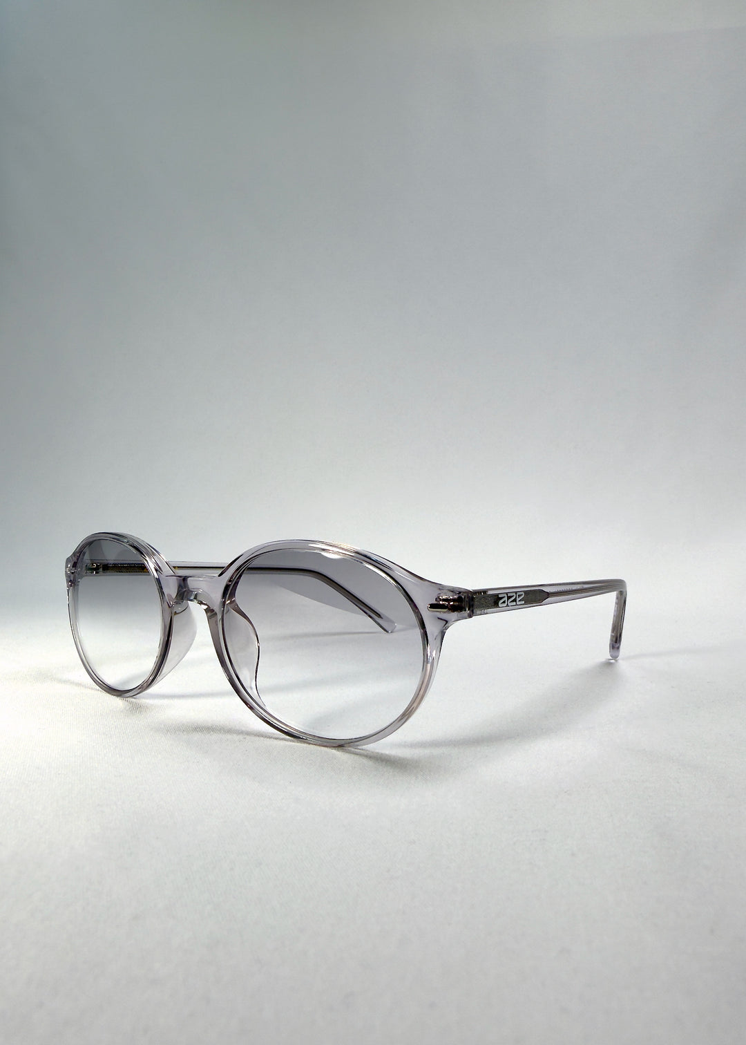 Front-angle view of Glint Softint sunglasses in Crystal Verge highlighting transparent grey frame and softly smoked lenses with UV400 protection.