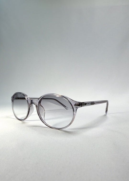 Front-angle view of Glint Softint sunglasses in Crystal Verge highlighting transparent grey frame and softly smoked lenses with UV400 protection. 