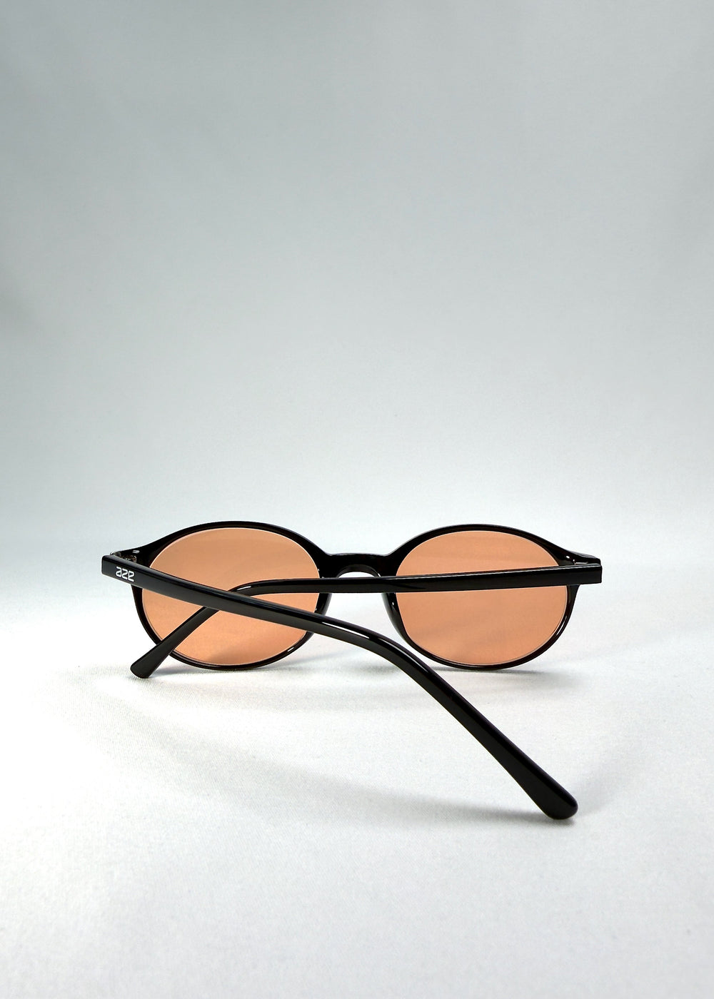 Back-angle view of Glint Softint sunglasses in Obsidian Beam showing slender acetate temples and warm amber lenses. #color_obsidian-beam