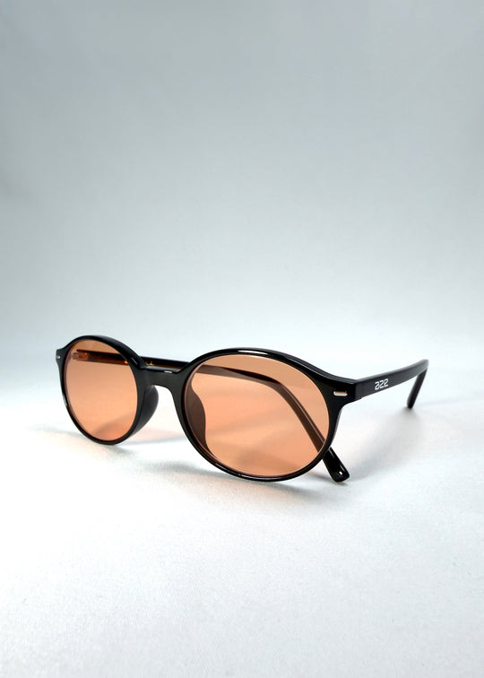 Close-up front-angle view of Glint Softint sunglasses in Obsidian Beam, emphasizing the amber lens tone and glossy acetate texture. 