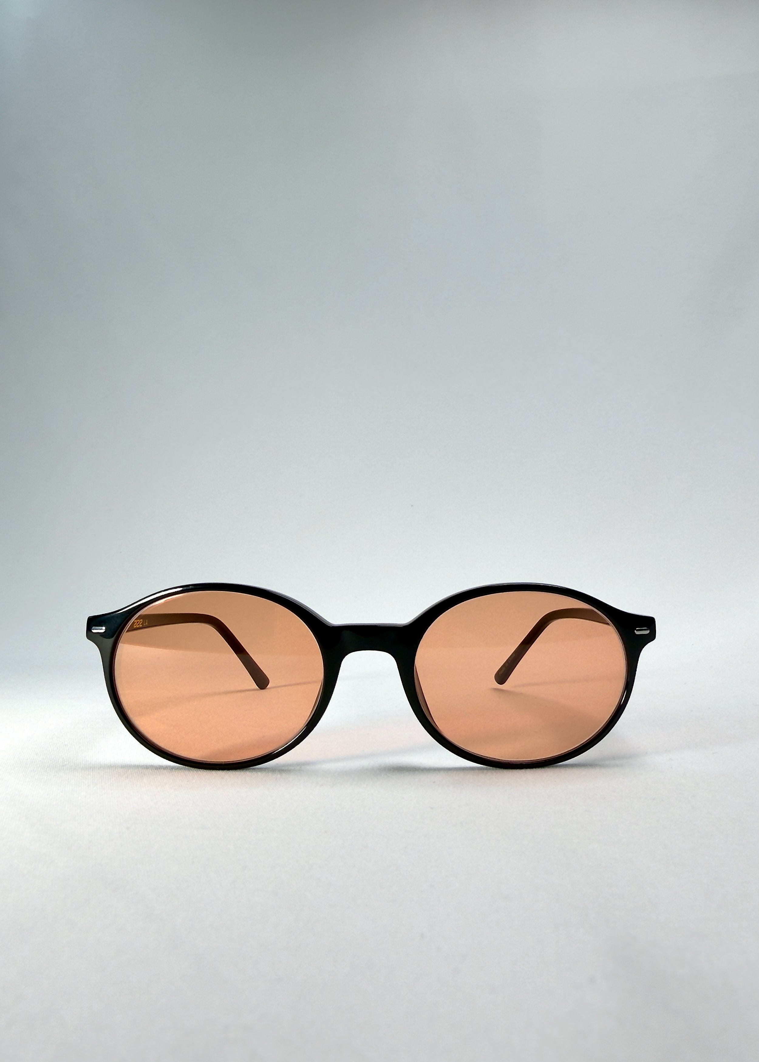 Front view of Glint Softint sunglasses in Obsidian Beam, highlighting the rounded black frame and lightly tinted amber lenses.