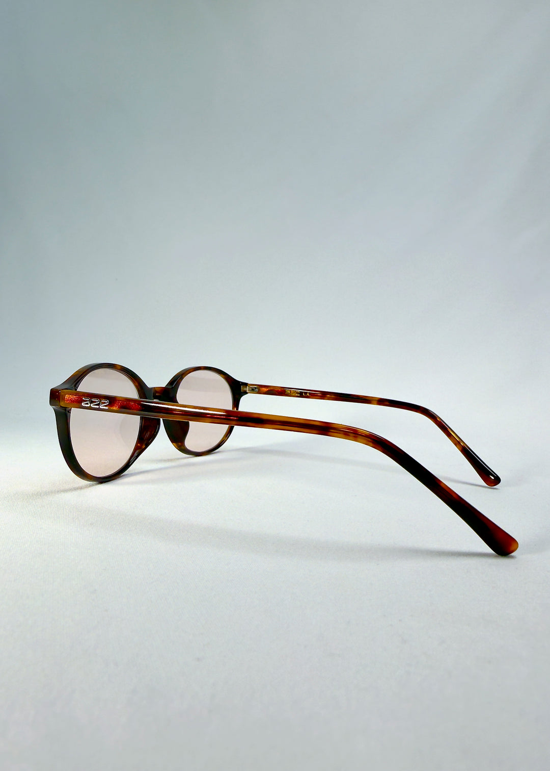 Back-angle view of Glint Softint sunglasses in Umber Ripple showing warm tortoise acetate frame and rose-tinted lenses.