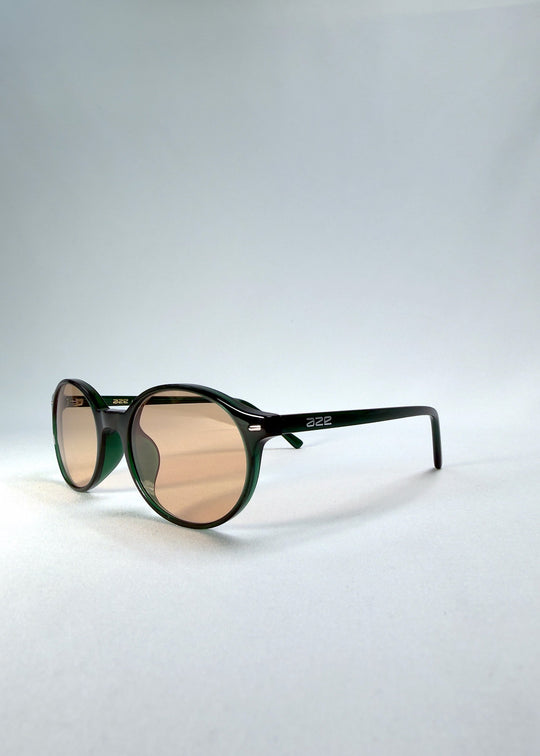 Front-angle view of Glint Softint sunglasses in Verdant Halo highlighting polished green acetate and softly tinted amber-rose lenses. 